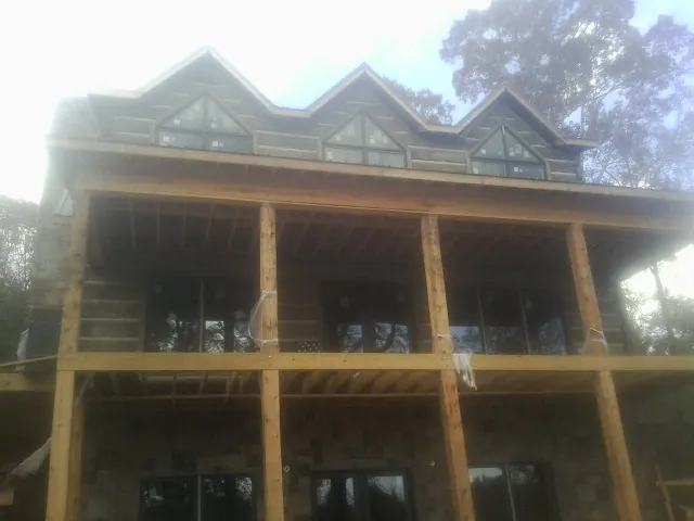 Dormers and porch framing on a large log home under construction — Roof Coating work by our crew in Gambell