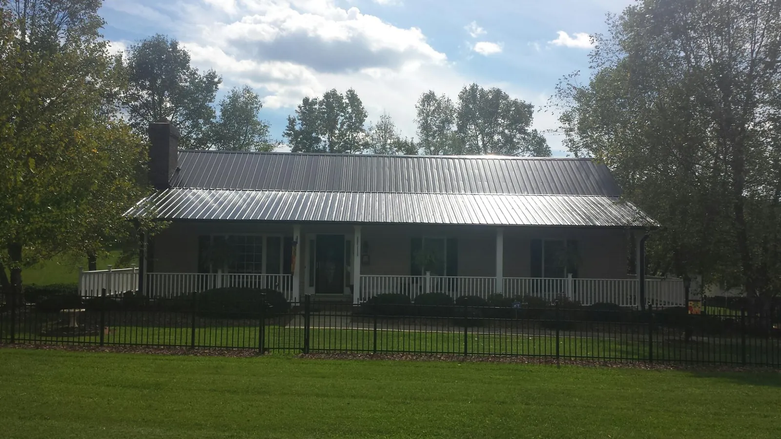 Gray metal roof on a brick ranch with a full width front porch — Gutter Guard Installation work by our crew in Gambell