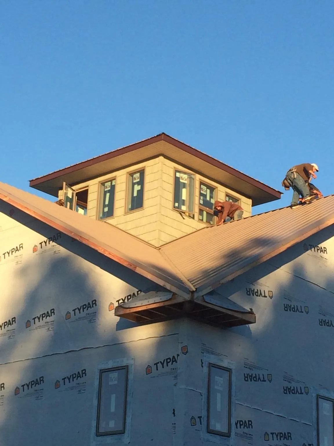 Roofers working around a rooftop cupola on a new metal roof at sunset — Roof Waterproofing in Gambell by Roofing Brothers